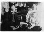Francis, and it must be Lucy and most likely William on the right. This picture looks different from most pictures of Lucy, so it might seem like it could be Bertha. However, the picture on the organ right next to Francis Bundy's moustache is plainly the picture of June Bundy standing in a chair when she was three years old. Also note the picture of William and Emeline on the organ behind the music stand. (Original: Janet Lucius)